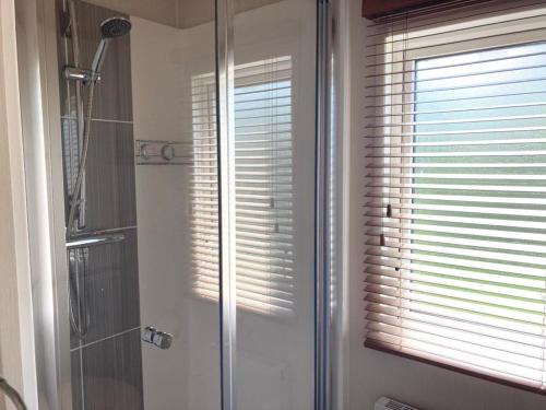 a bathroom with a shower and a window with blinds at Vogue at Primrose in Reighton