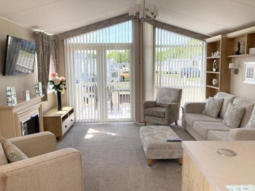 a living room with a couch and chairs and a tv at Vogue at Primrose in Reighton
