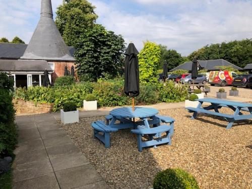 two picnic tables and an umbrella in a yard at The Stables Kersey Mill in Whatfield