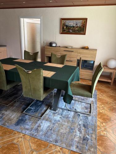 a dining room with a green table and chairs at Ferienhaus Annerose in Wendisch Rietz