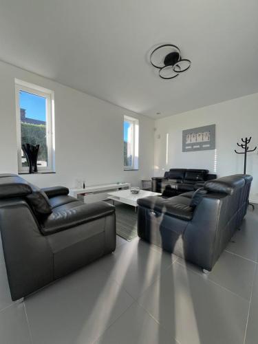 a living room with leather couches and a table at Moderne Villa aux portes de Bruxelles! in Grimbergen