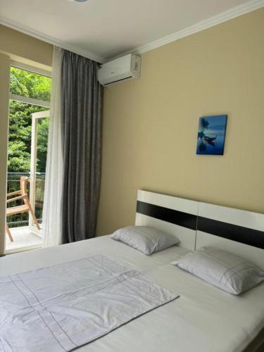 a bedroom with a white bed with a window at Villa Royal Realm in Batumi
