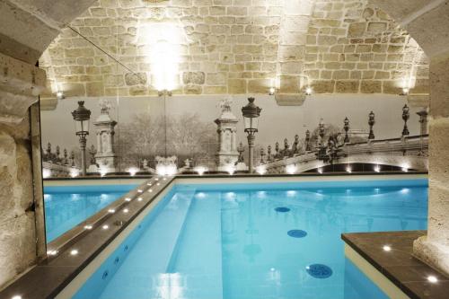 an indoor swimming pool with blue water in a building at Hotel La Lanterne & Spa By Timhotel in Paris