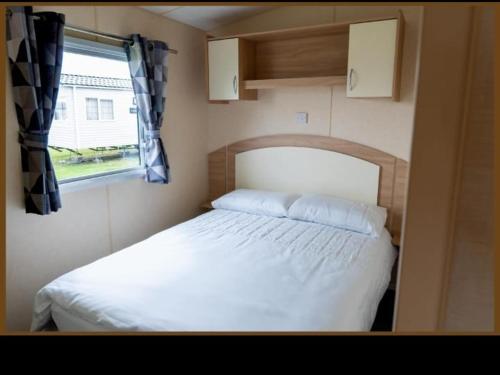 a small bedroom with a bed and a window at Whitley Bay Caravan in Hartley