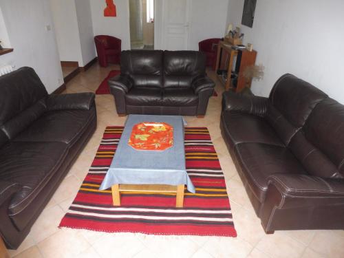 a living room with two leather couches and a table at Le Numéro 4 ! in Labruguière