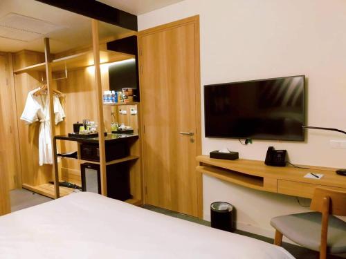 a hotel room with a bed and a desk with a television at Zazz Urban Ho Chi Minh in Ho Chi Minh City