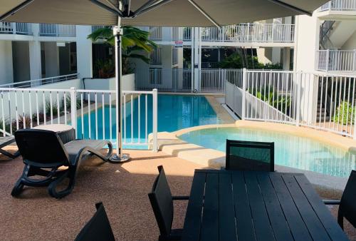 a swimming pool with a table and chairs and an umbrella at Strand to Stadium - Perfect central location in Townsville City in Townsville