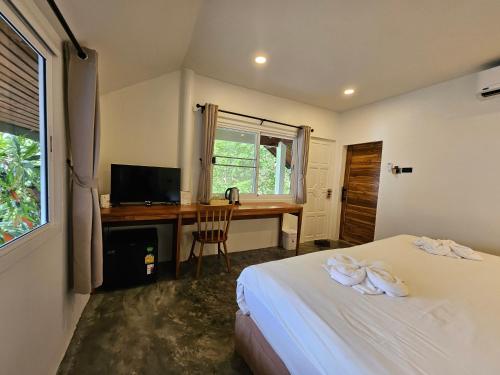 a bedroom with a bed and a desk with a computer at Phangan Utopia Resort in Mae Haad