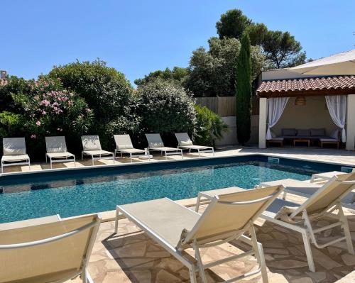 - un groupe de chaises et une piscine dans l'établissement L'Oustau de la Colline - Villa avec piscine privée chauffée 12 personnes au coeur du Luberon, à Cavaillon