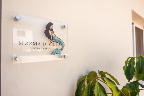 a mermaid wall sign on a wall with a plant at Mermaid Villa 16 in Ayia Napa