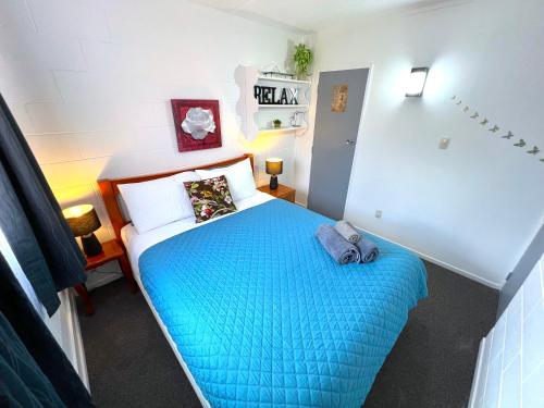 a small bedroom with a bed with a blue comforter at Parkview Holiday Homes "Opposite of Famous Kuirau Park" in Rotorua