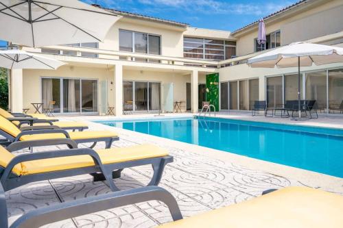 a hotel pool with lounge chairs and umbrellas at Casa da Naia - by Proguest in Adaúfe