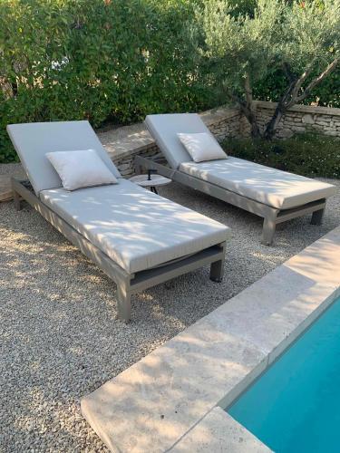 two beds sitting next to a swimming pool at Le Cabanon de Livia avec piscine privée in Cucuron
