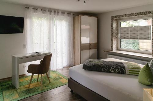 a bedroom with a bed and a desk and a window at Pension Waldhorn in Aidlingen