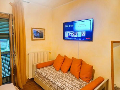 sala de estar con sofá y TV en la pared en The Camelia, our Room with Lake View, Private Bathroom and Dedicated Parking at the Villa Isabella Stresa, en Stresa