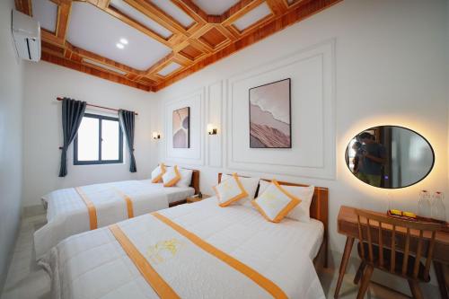 a bedroom with two beds and a table and a mirror at BÌNH MINH HOTEL - ĐẢO PHÚ QUÝ in Cu Lao Thu