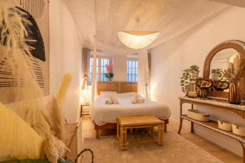 une chambre avec un lit, une table et un miroir dans l'établissement Coucher Bohème, à Orléans