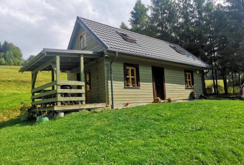 Una pequeña casa en una colina cubierta de hierba en un campo. en Zielony Domek, en Żabnica