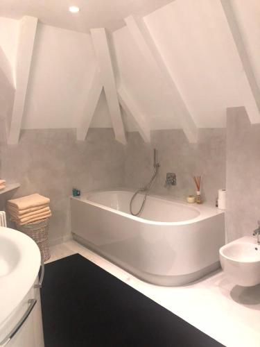 een witte badkamer met een bad en een wastafel bij Penthousetraum im Herzen Merans in Merano