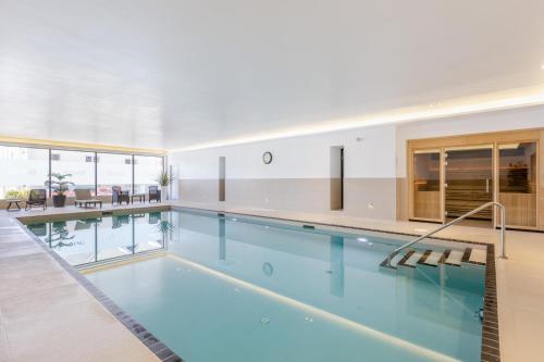 a swimming pool with blue water in a building at 1 Challacombe - Luxury Apartment at Byron Woolacombe, only 4 minute walk to Woolacombe Beach! in Woolacombe