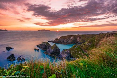 a sunset over the ocean with rocks in the water at Lavarna House in Annascaul