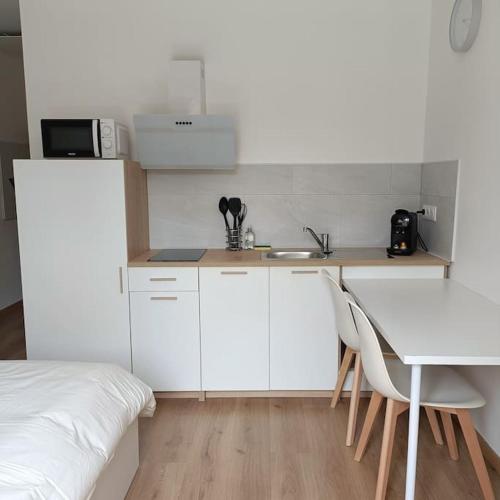 une cuisine avec un évier et une table avec des chaises dans l'établissement L'Escale Châtillonnaise - Le Voyageur, à Châtillon-sur-Loire