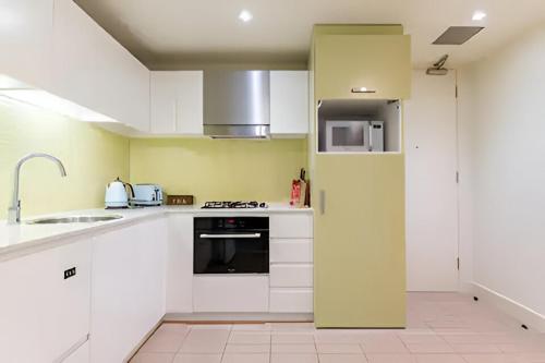 a kitchen with white cabinets and a stove top oven at SUNSET GETAWAY GLENELG in Glenelg