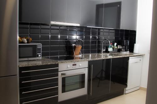 a kitchen with a black tiled wall at Modern Beach Apartment - La Maca in Tamariu