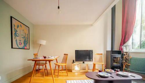 un salon avec une table, des chaises et une télévision dans l'établissement Maisonette indépendante tout confort et son jardin, à Paris