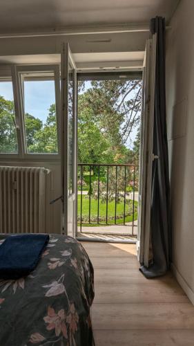 - une chambre avec un lit et une porte donnant sur un balcon dans l'établissement L'appartement de la gare, à Besançon