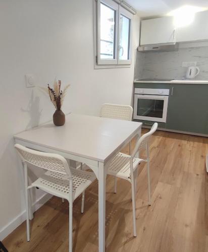 une table blanche et des chaises dans une cuisine dans l'établissement Studio moderne 4 pers max proche Paris, à Fontenay-lès-Briis