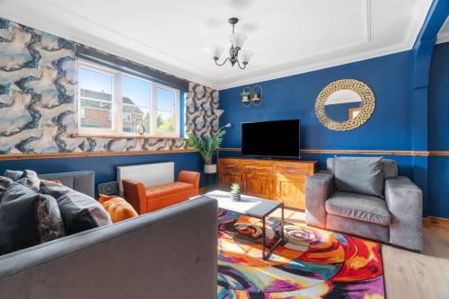 a blue living room with a couch and a tv at Detached House in Ashford with Free Parking and Hot Tub - Sleeps 10 in Ashford