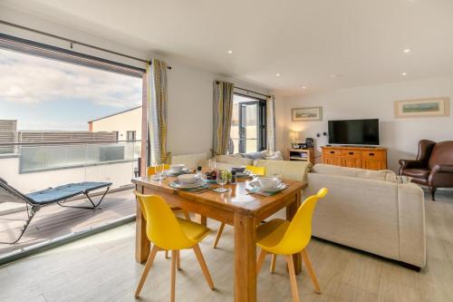 a living room with a wooden table and yellow chairs at 7 Middlecombe - Luxury Apartment at Byron Woolacombe, only 4 minute walk to Woolacombe Beach! in Woolacombe
