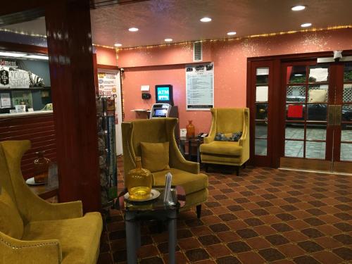 a waiting room with yellow chairs and a table at Tradewinds Airport Hotel in Inglewood