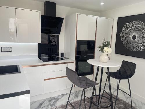 a white kitchen with a table and chairs at Modern-luxury 1bedroom-EnsuiteBathroom-Garden-Wifi in Basildon