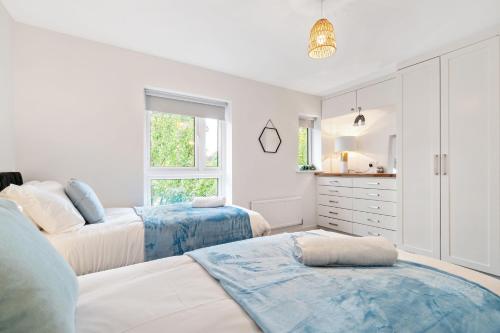 a white bedroom with two beds and a kitchen at Ashford Home off M20 with 2x Private Parking - Long Stays in Kent