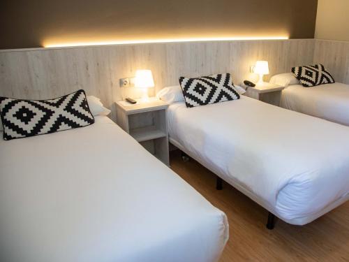two beds in a hotel room with two lamps at Hotel Restaurante Cadosa in Soria