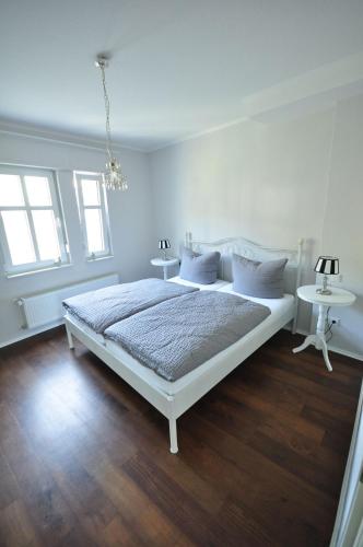 a white bedroom with a bed and two tables at Gästezimmer im Weingut Amlinger&Sohn in Neef