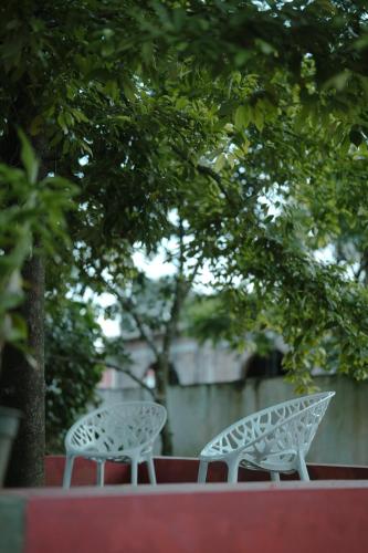 two white tables and chairs sitting under a tree at Marari Bobans villa in Mararikulam