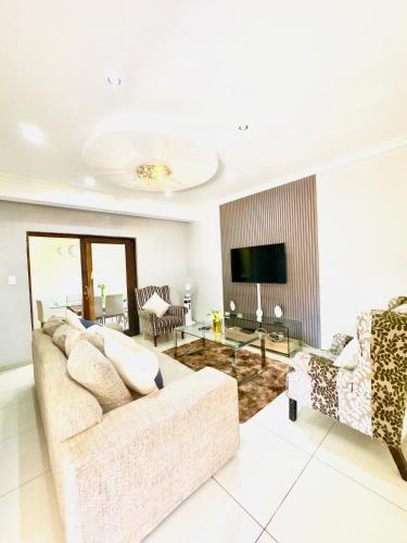 a living room with a couch and a television at Townhouse on 6526 Boiketlo Street, Golfview in Mahikeng