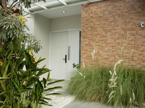 a white door in a brick building with plants at Villa Tjokro in Yogyakarta