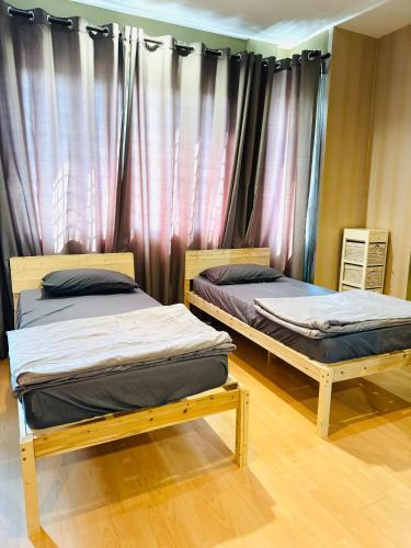 two beds sitting in a room with curtains at HmHome-Four in Rumah Ide