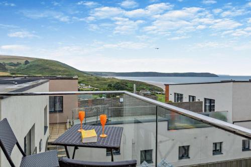 a balcony with a table with two drinks on it at 12 Putsborough - Luxury Apartment at Byron Woolacombe, only 4 minute walk to Woolacombe Beach! in Woolacombe