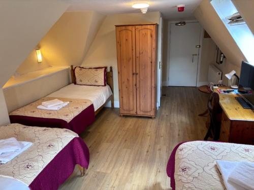 a attic room with two beds and a desk at Cumberland Hotel in Edinburgh