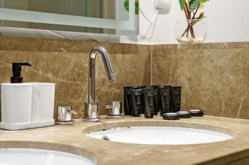 een wastafel in de badkamer met een kraan en een zeepdispenser bij FIRST CLASS 3BR Burj Khalifa & Fountain View in Dubai