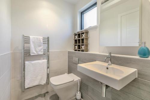 a bathroom with a sink and a toilet and a mirror at 6 Putsborough - Luxury Apartment at Byron Woolacombe, only 4 minute walk to Woolacombe Beach! in Woolacombe
