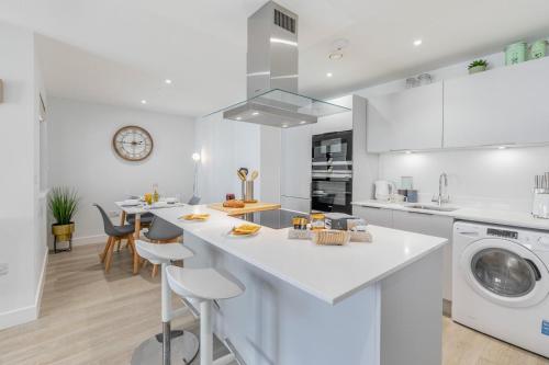 a white kitchen with a washer and dryer at 6 Putsborough - Luxury Apartment at Byron Woolacombe, only 4 minute walk to Woolacombe Beach! in Woolacombe