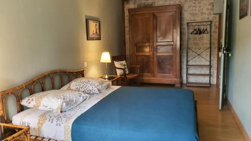 a bedroom with a blue bed and a wooden door at Le Pressoir de Marsac in Marsac
