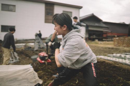 a woman swinging a baseball bat in a yard at hinatabocco guesthouse Japanese warehouse in Miyaki