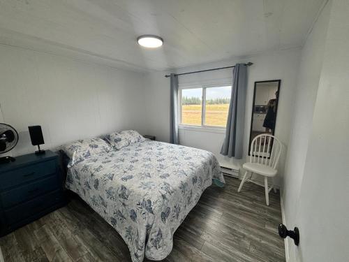 a bedroom with a bed and a window and a chair at Cottages On PEI-Oceanfront in Bedeque